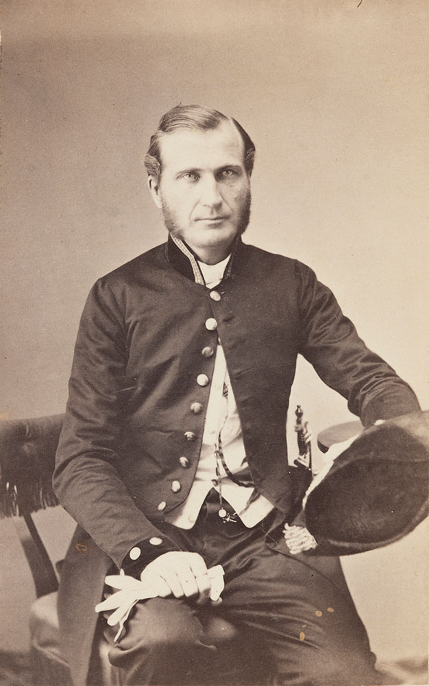 Nimismiehen virkapukuun 1800-luvun loppupuolella kuului tumma sortuutti ja juhlakäytössä kaksikolkkahattu ja virkamiekka. Arkisin käytettiin tummanvihreää virkalakkia. Sauvon nimismies Carl Johan Sevonius. Kuva: Museovirasto.